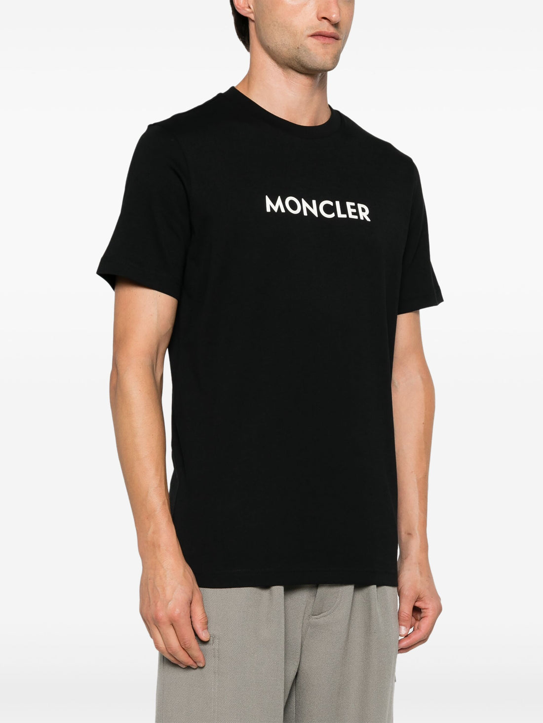 Side angle on model of the MONCLER Logo Print Cotton T-Shirt in Black, highlighting the premium cotton fabric and relaxed fit.